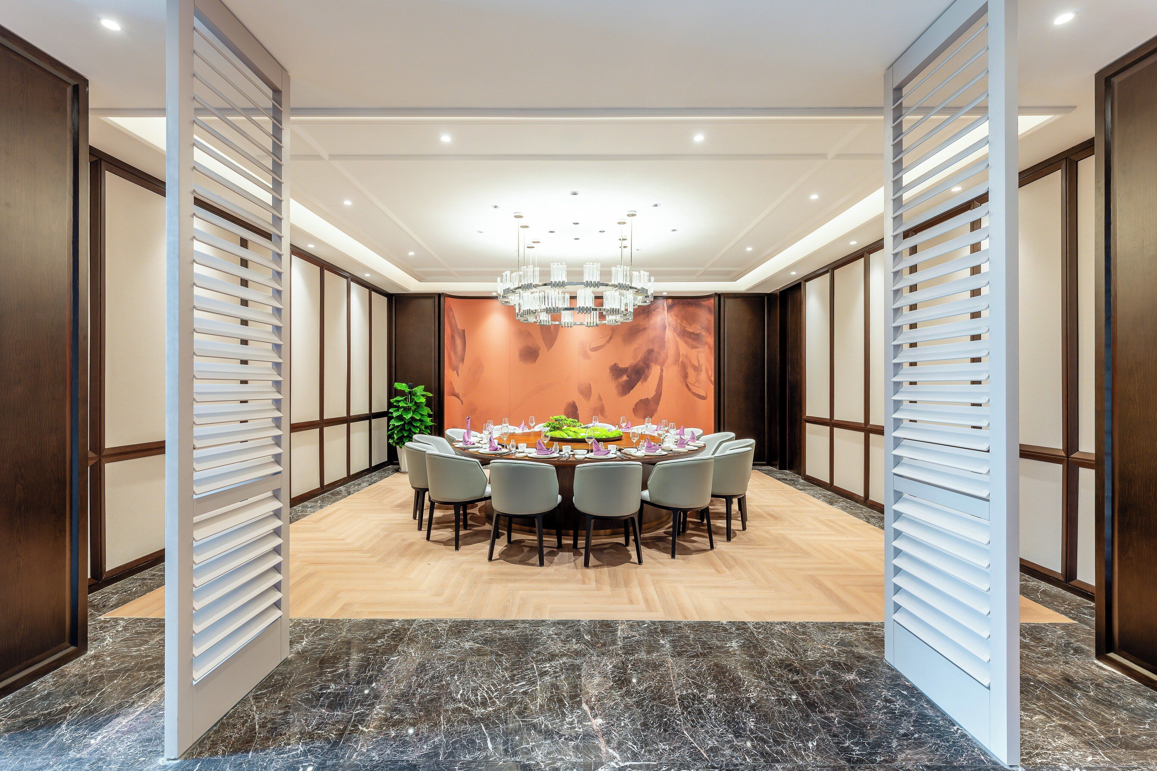 A conference room with a round table, chairs, a chandelier, and a large wall mural.