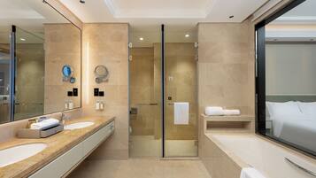 Un baño moderno con dos lavamanos, cabina de ducha de vidrio y un espejo grande.