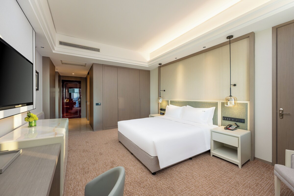 Une chambre d’hôtel avec un grand lit, des tables de chevet, un bureau et une télévision.