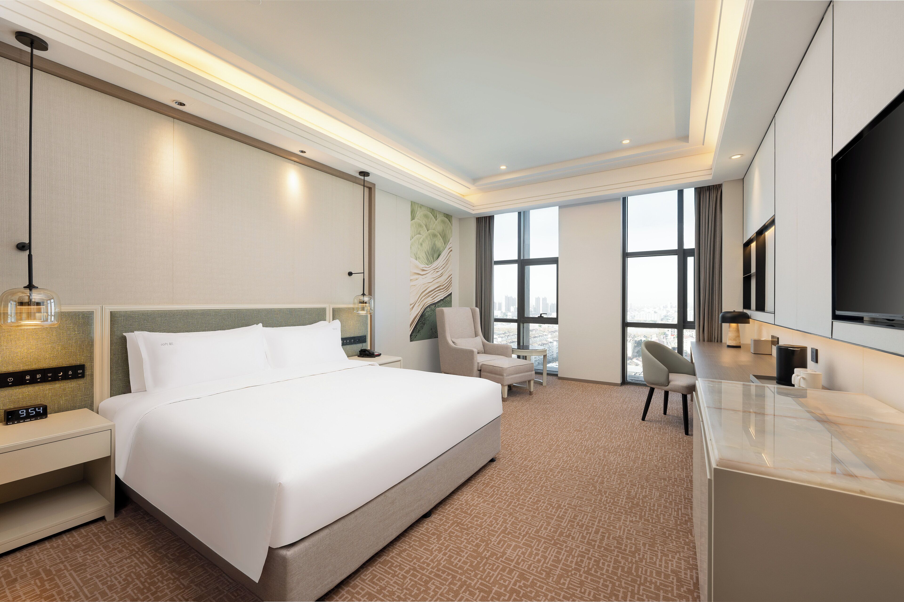 Habitación de hotel moderna con una cama grande, un escritorio, una silla y vistas a la ciudad desde las ventanas.