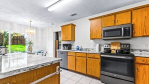 A kitchen with wooden cabinets, a stainless steel stove, a microwave, and a marble countertop. - 4 bedrooms, 2 bathrooms 
 (Dallas)