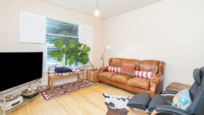 A living room with a leather sofa, a television, a large plant, and a wooden coffee table. - Main Street Gem-Steps to Downtown Telluride (Telluride)