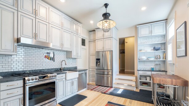 A modern kitchen with white cabinetry, stainless steel appliances, and a wooden floor. - Main Street Gem-Steps to Downtown Telluride (Telluride)