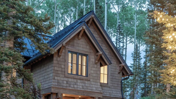 Une maison en pierre, avec un chemin en pierre menant à l’entrée, entourée d’arbres et de verdure.