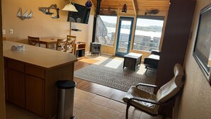 Een moderne keuken met een centraal eiland, een houten eettafel en stoelen. Een groot raam biedt uitzicht op de stad.