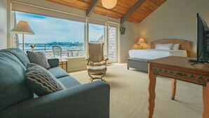 A room with a bed, a sofa, a chair, a table, and a TV.