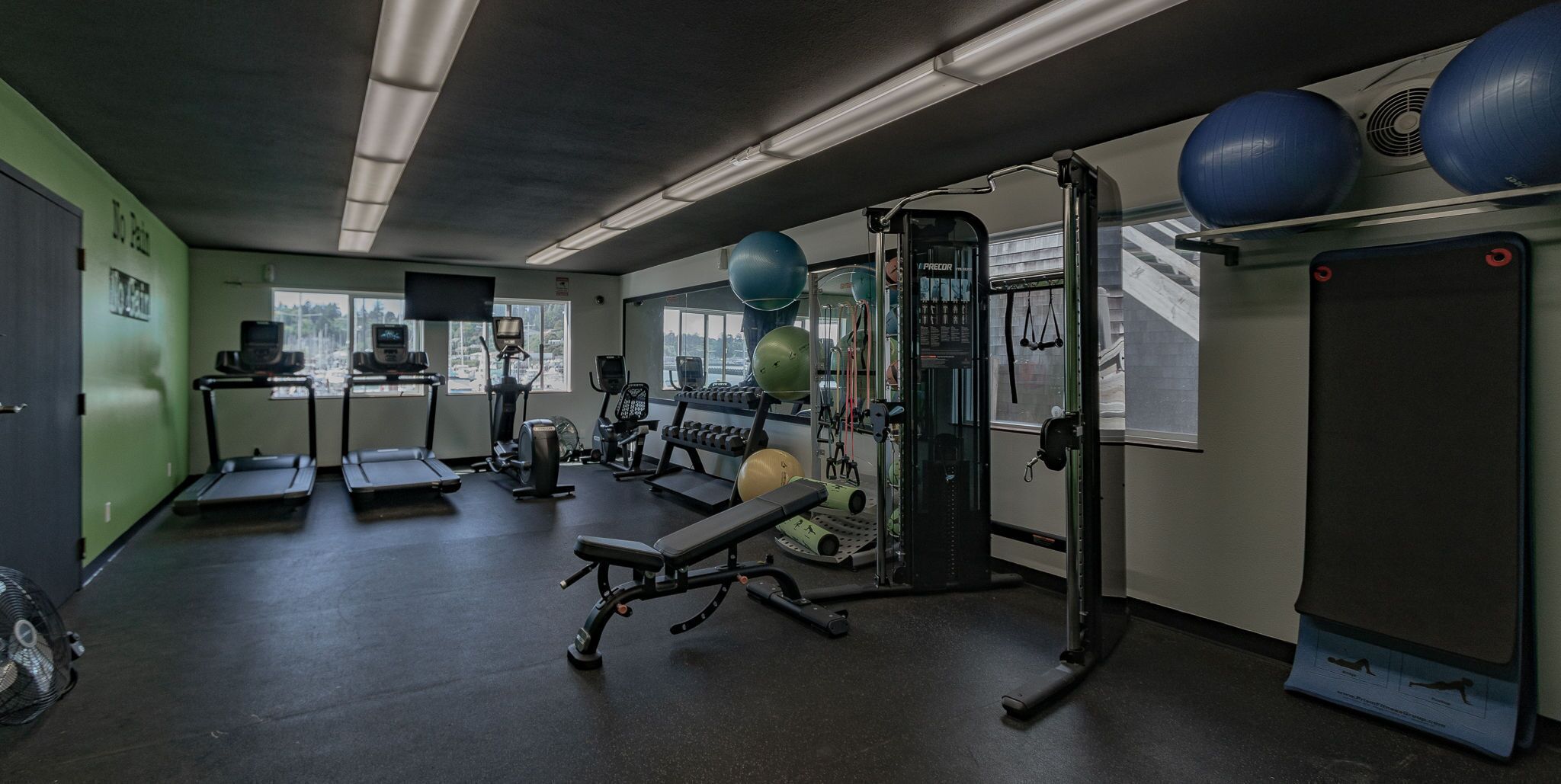 A gym with treadmills, weight machines, and exercise balls.