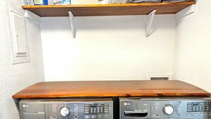 A laundry area with two front-loading LG washing machines and a wooden shelf above them. - BALLOON FESTIVAL experience ABQ in style newly renovated 2BD/1BA apartment (Albuquerque)