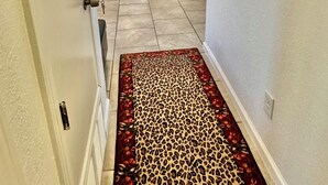 A hallway with a leopard print carpet, a door on the left, and a white door at the end. - BALLOON FESTIVAL experience ABQ in style newly renovated 2BD/1BA apartment (Albuquerque)