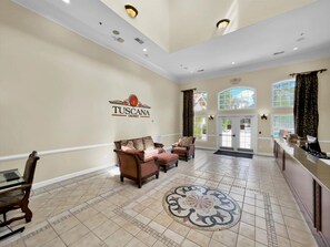 Relax in the Tuscana Orlando lobby, featuring a spacious area with a high ceiling, comfortable seating, and a beautiful rug.