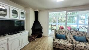 Uma sala de estar com lareira, televisão e sofá com estofamento floral.