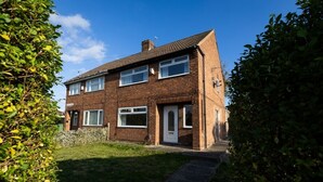 A two-story brick house with a front garden, a visible front door, and a pathway leading to the entrance. - Charming 3-bedroom house with WiFi and free parking within compound in Thornaby (Thornaby)