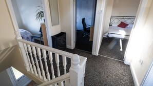 A bedroom with a bed, a chair, and a desk. There is a staircase leading to another room. - Charming 3-bedroom house with WiFi and free parking within compound in Thornaby (Thornaby)