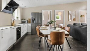 Una cocina moderna con gabinetes blancos, un refrigerador de acero inoxidable y un microondas integrado.