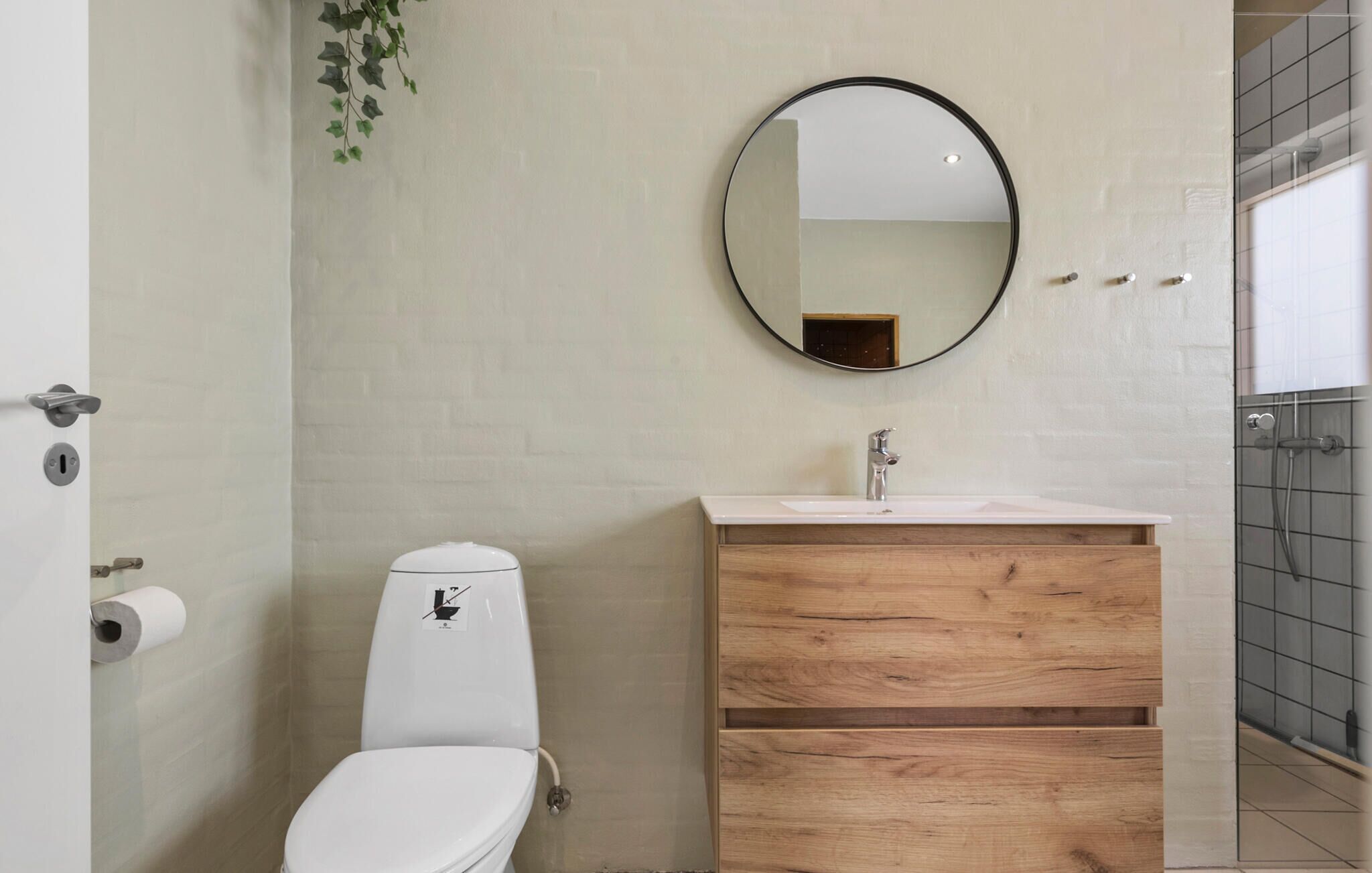 Un baño con inodoro, lavamanos con espejo y un mueble de madera.