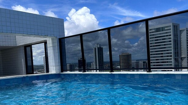 Piscina com vista para a cidade, arquitetura moderna e céu limpo.