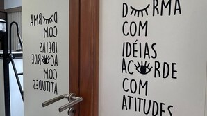 Uma porta com moldura de madeira e puxador de metal. A porta possui duas placas com texto em língua estrangeira.