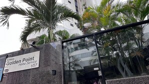 Entrada de um edifício com uma placa que diz 'Golden Point Home Service 657'.