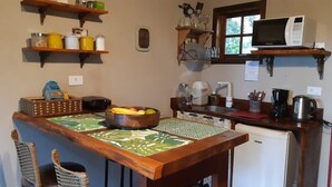 A compact kitchen with wooden shelves, a refrigerator, and a microwave.
