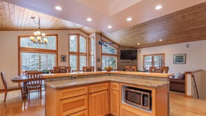 A spacious kitchen with wooden cabinetry, a granite countertop, and a built-in microwave. - *New* Tahoe Donner Cabin*Swiss Chalet* (Truckee)