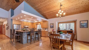 A spacious kitchen with wooden cabinets, a central island, and a dining area with a wooden table and chairs. - *New* Tahoe Donner Cabin*Swiss Chalet* (Truckee)