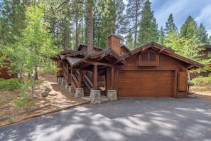 A cabin with a stone foundation, wooden exterior, and a garage.