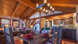 A spacious living room with a wooden dining table set for a meal, a staircase leading to another level, and a kitchen area with modern appliances.