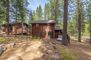 A cabin with a deck and hot tub, surrounded by pine trees. - Cozy Northstar Home ~Northstar Mountain~ (Truckee)