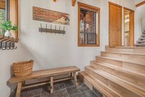 Un banco de madera, un perchero de pared, un letrero rústico y una escalera con escalones de madera.