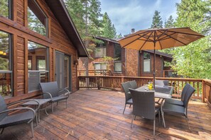 A wooden deck with outdoor furniture, a large umbrella, and a view of a cabin with a deck. - Cozy Northstar Home ~Northstar Mountain~ (Truckee)