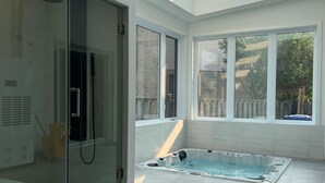 A modern bathroom with a glass shower enclosure, a built-in jacuzzi, and large windows allowing natural light. - Luxurious home with indoor pool and spa (Brossard)