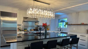 A modern kitchen with a central island, stainless steel appliances, and a chandelier. - Luxurious home with indoor pool and spa (Brossard)