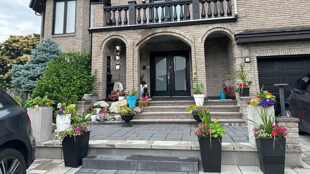 A two-story house with a brick facade, a balcony, and a garage. - Luxurious home with indoor pool and spa (Brossard)