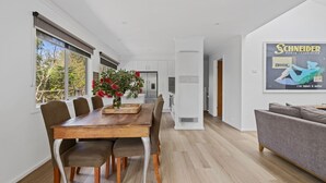 A modern kitchen with white cabinets, a built-in oven, and a stainless steel refrigerator. - Beachside Family Haven (Inverloch)