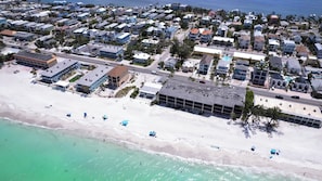 An aerial view of a coastal residential area with beachfront properties, a parking lot, and a swimming pool. - Island Living Awaits at Sand Dollar Villa Three Bedroom/Two Bath STEPS from GULF BEACHES!! (Bradenton Beach)