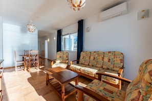 A living room with a sofa, chairs, a wooden coffee table, and a dining table.