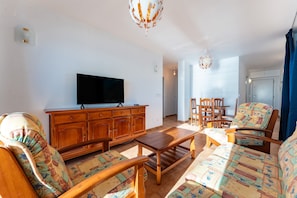 A living room with a television, wooden furniture, and patterned cushions.