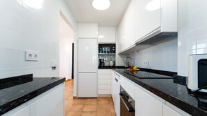 Una cocina moderna con armarios blancos, encimeras negras y un horno empotrado.