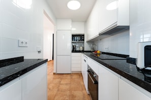 Una cocina moderna con armarios blancos, encimeras negras y un horno empotrado.
