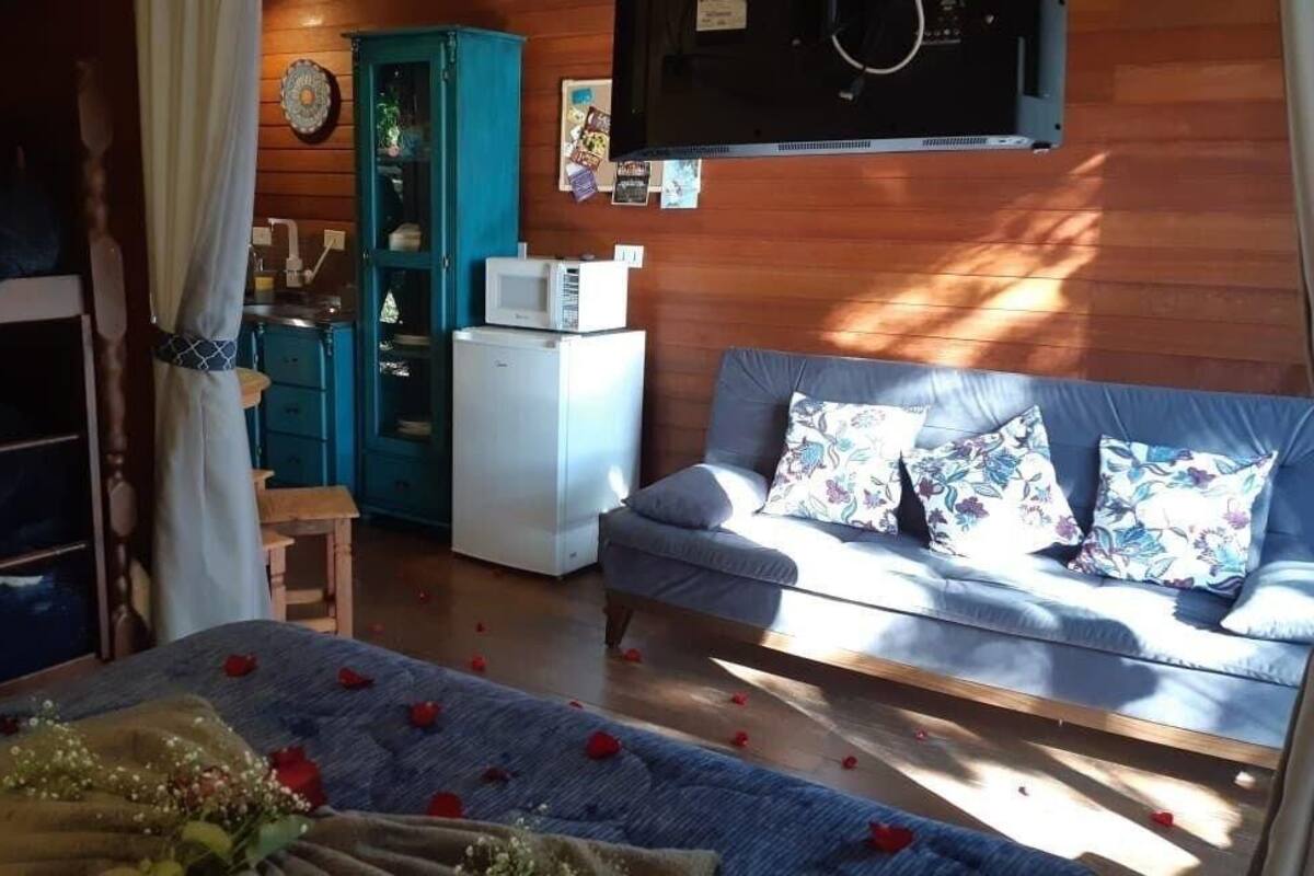 Ein gemütliches Zimmer mit einem Bett, einer Couch, einem kleinen Tisch mit Blumenvase, einer Mikrowelle und einem Schrank.