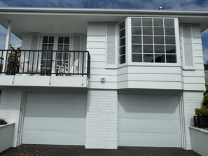 Ein zweistöckiges Haus mit Garage, einem Balkon mit schwarzem Geländer und einem dekorativen Wappen an der Wand.