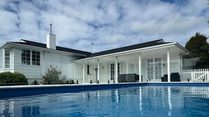 A modern house with a swimming pool, large windows, and a covered patio area.