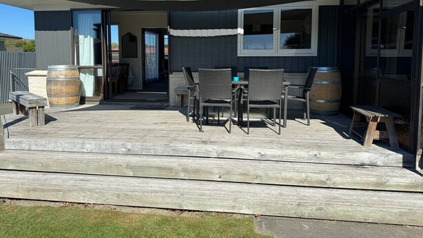 Un patio couvert avec une table et des chaises, des tonneaux en bois et un petit banc.