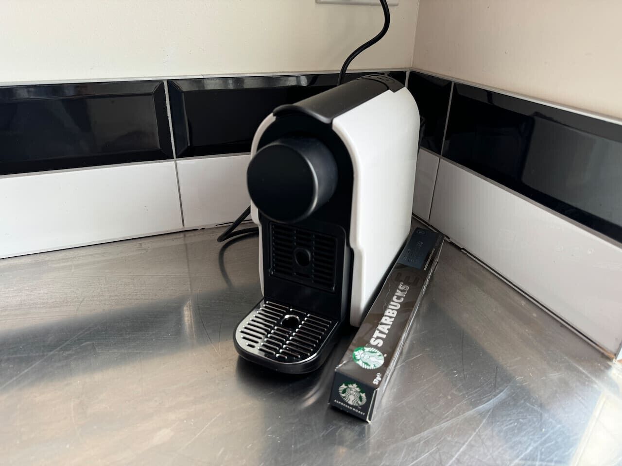 A coffee machine with a Starbucks branded coffee pod beside it.