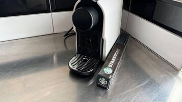 A coffee machine with a Starbucks branded coffee pod beside it.