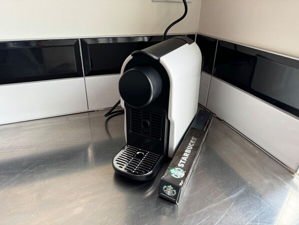 En kaffemaskin med en kaffekapsel från Starbucks bredvid.