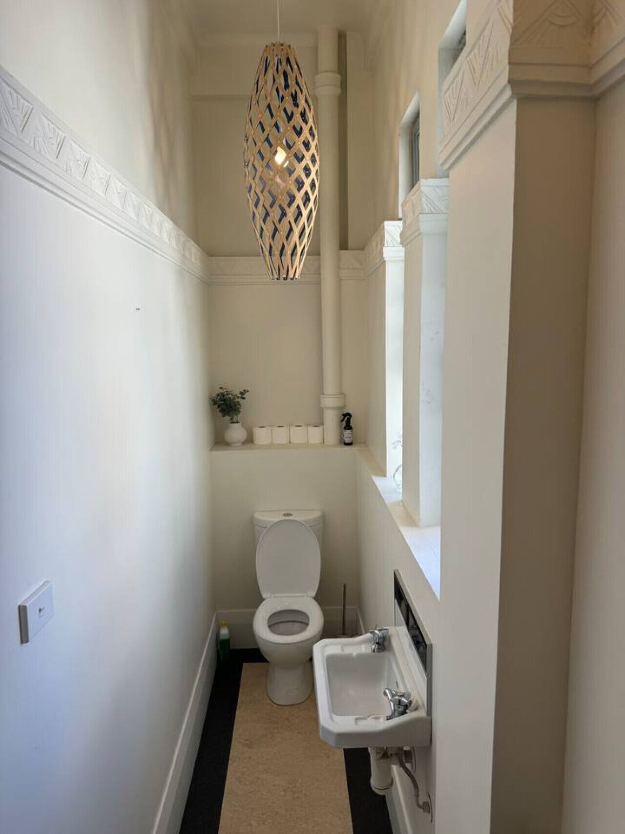 Une petite salle de bain comprenant des toilettes, un lavabo et un luminaire décoratif suspendu.
