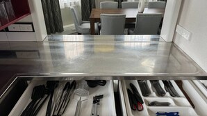 Eine Küche mit einer Edelstahl Arbeitsplatte, einem Schubladeneinsatz für Besteck und einem Essbereich mit Tisch und Stühlen.