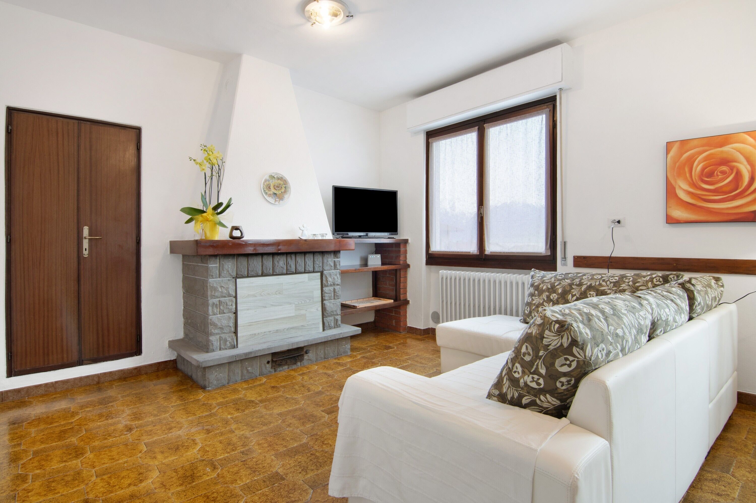 A living room with a fireplace, a television, a sofa, and a large window.