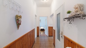 Un pasillo con paneles de madera, un corazón decorativo en la pared, una repisa con una planta y una puerta al final.